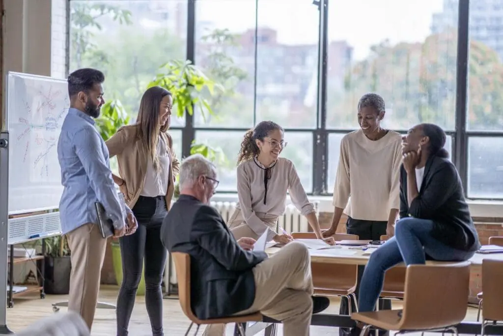 Happy employees around a table show the importance of great staff in homebuilder branding.
