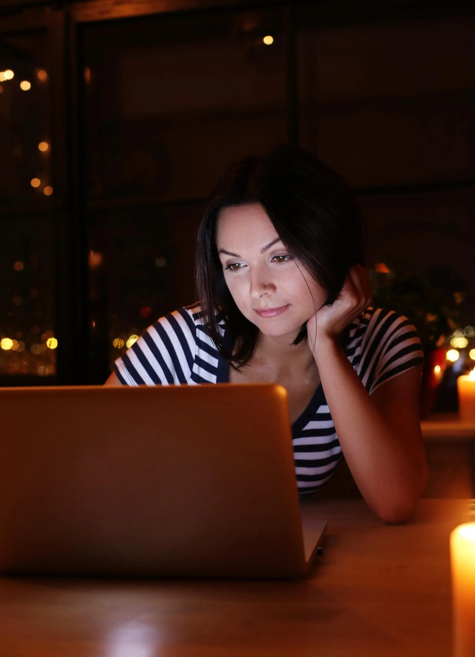 Woman browsing on her laptop at night
