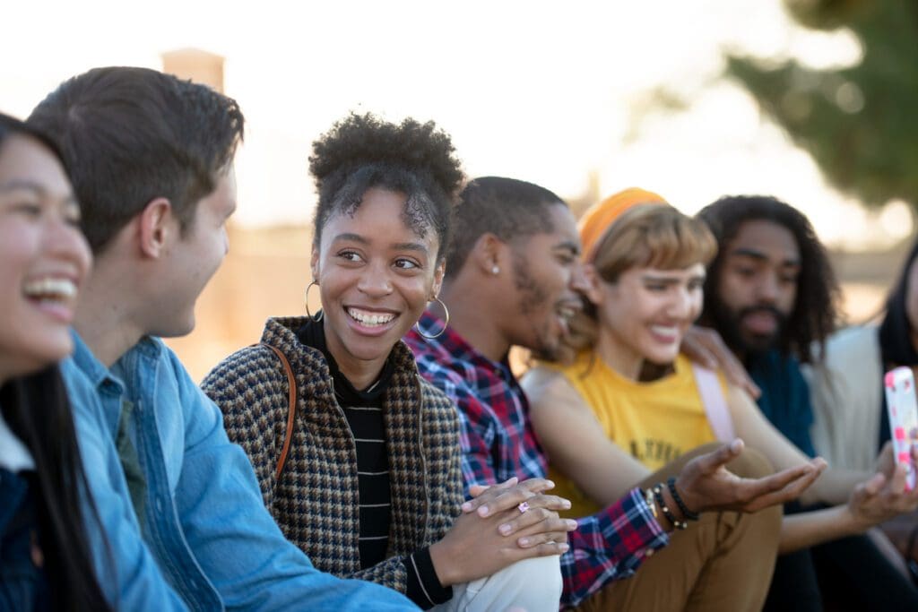 A diverse group of students sits on the steps of their higher education institution.