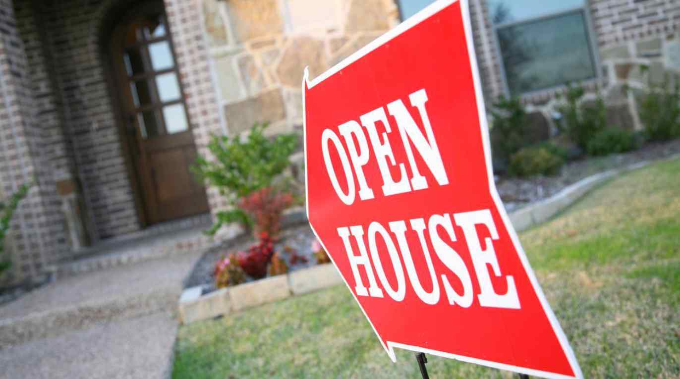 An open house sign out front of a new home is part of home builder advertising.