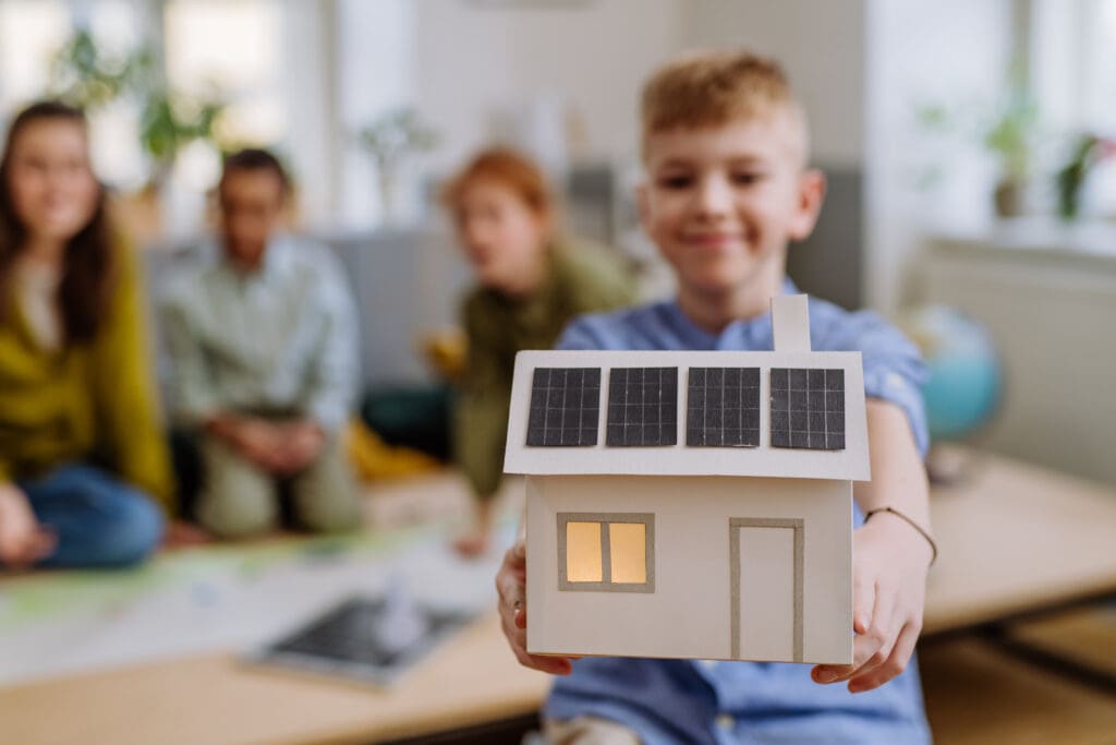 Little boy holding a solar-equipped model house