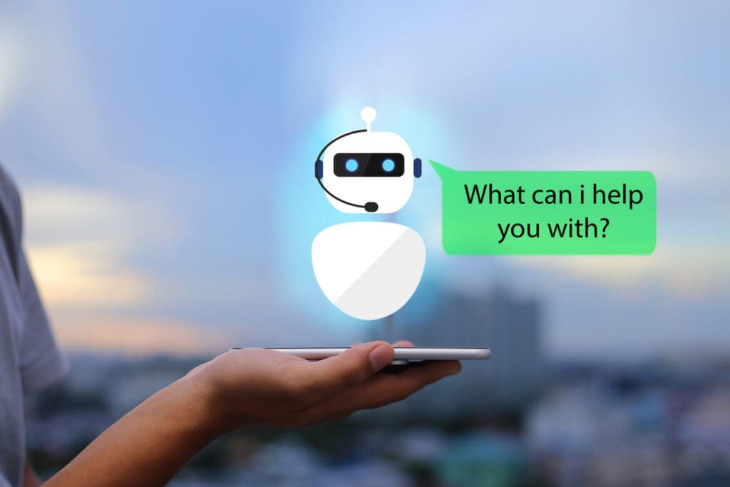 Hand holds phone with virtual chatbot sitting on top, illustrating conversational AI.