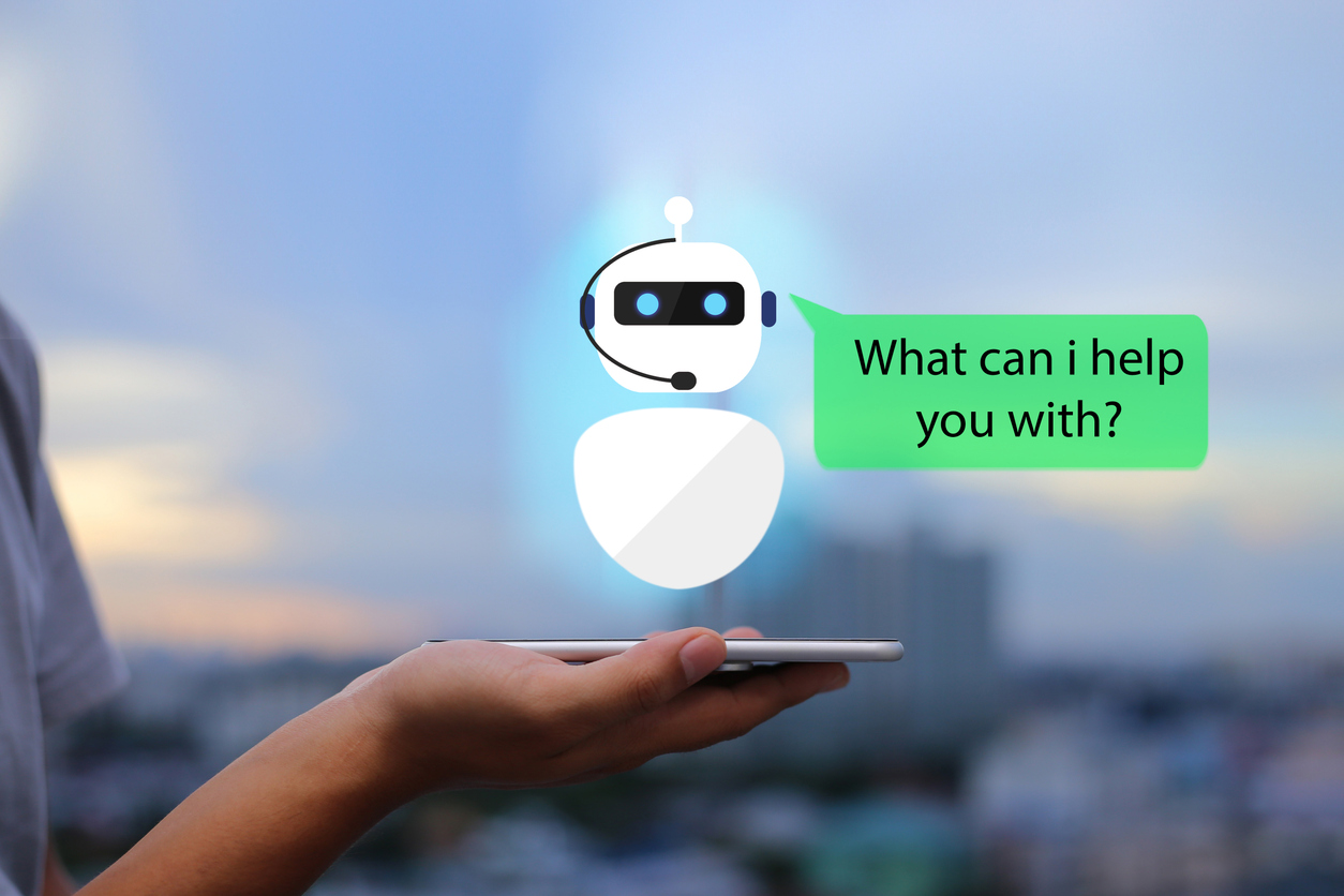 Hand holds phone with virtual chatbot sitting on top, illustrating conversational AI.