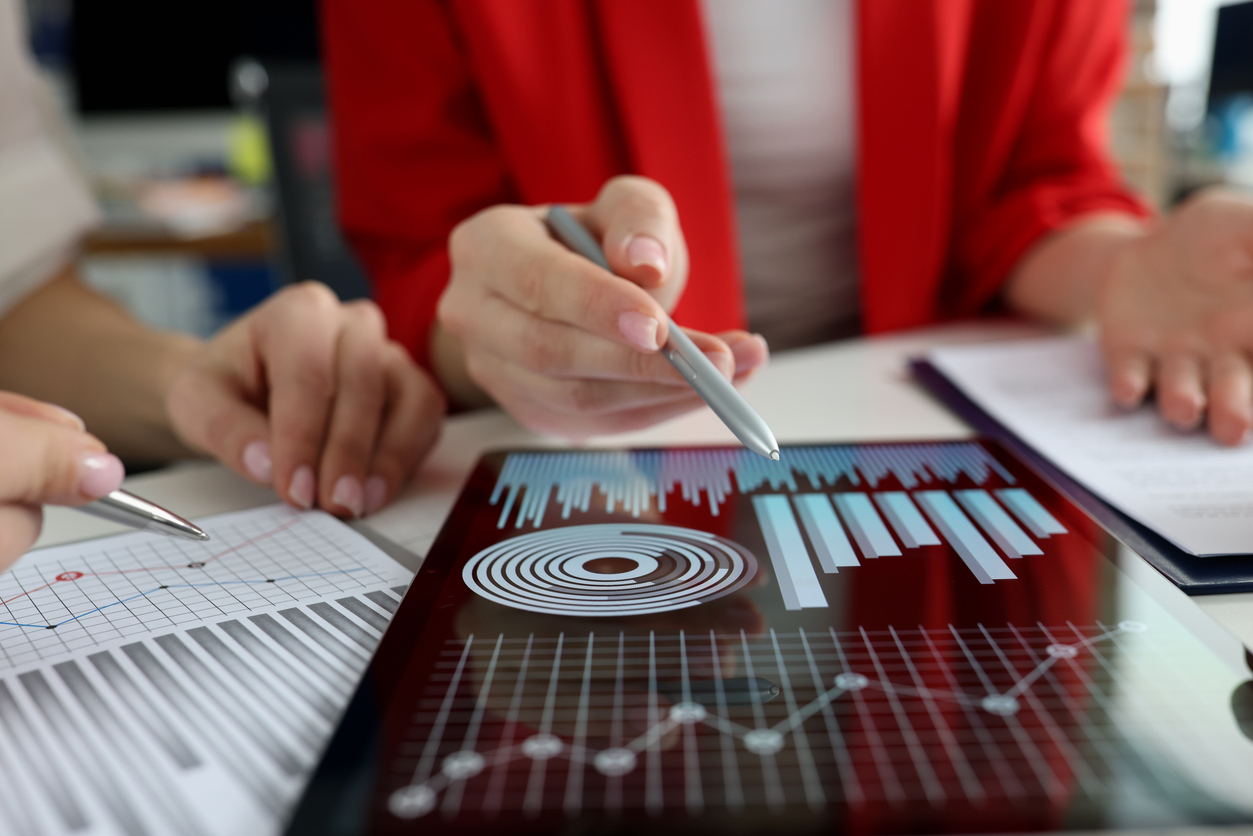 Woman looks at student acquisition metrics on a tablet. 