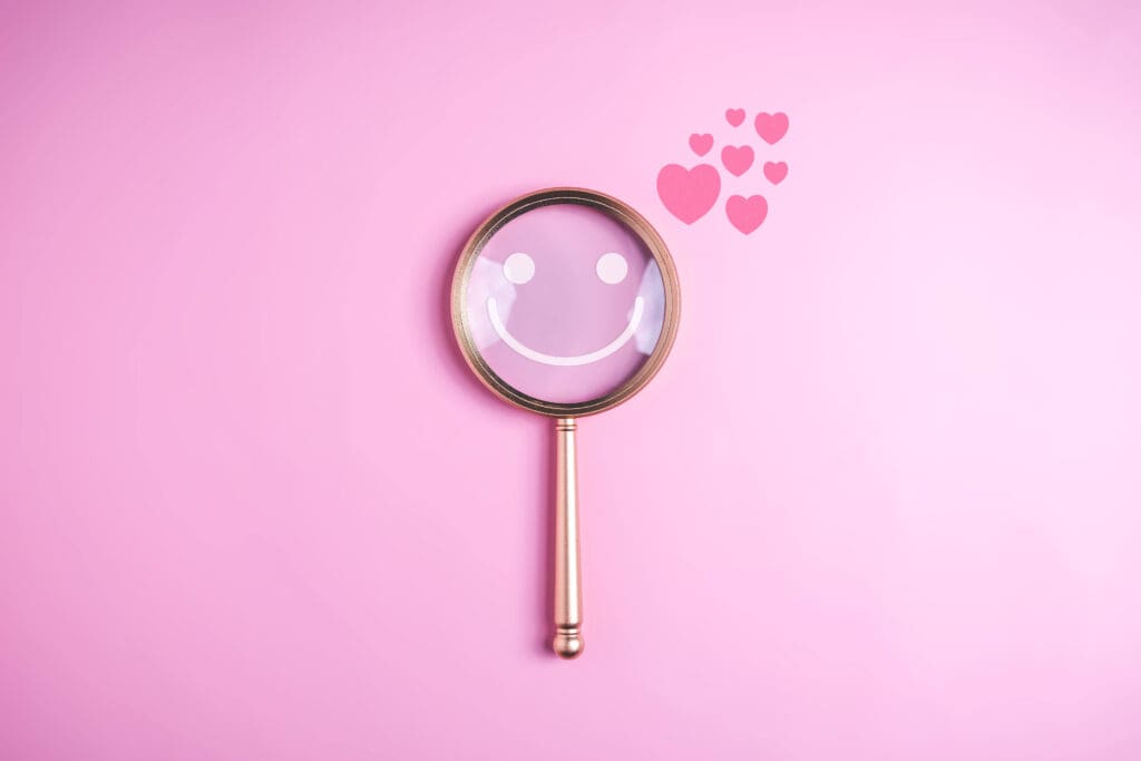 Magnifying glass with hearts on a pink background, representing reviews and searchability