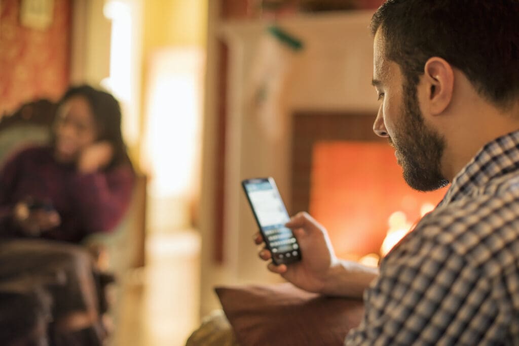 A man smiling looking at his phone during the holidays.