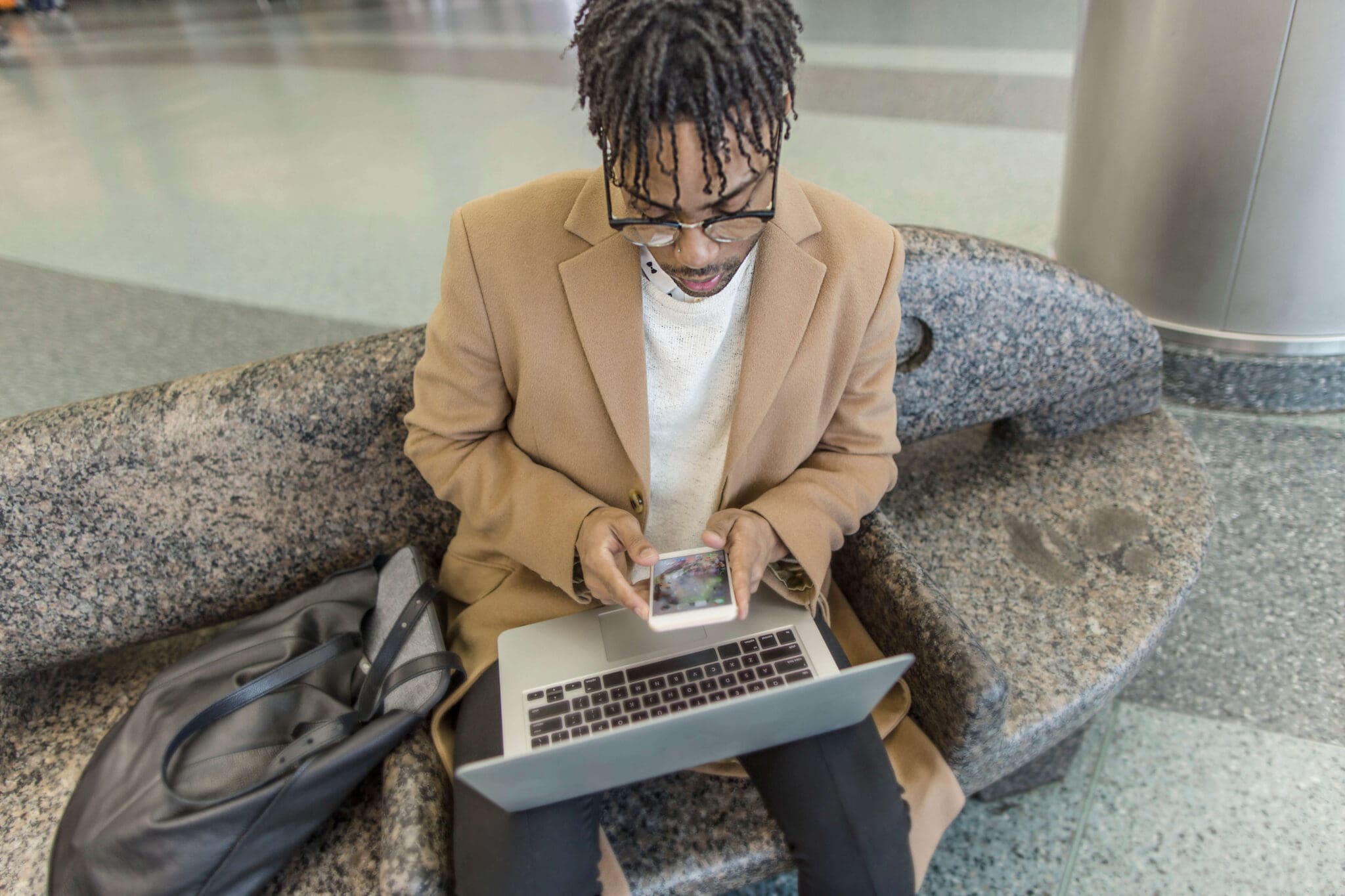 A young man using omnichannel marketing on his phone and laptop