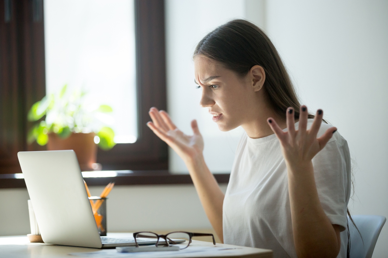 A woman is sitting at her laptop frustrated because of inaccurate information from AI.