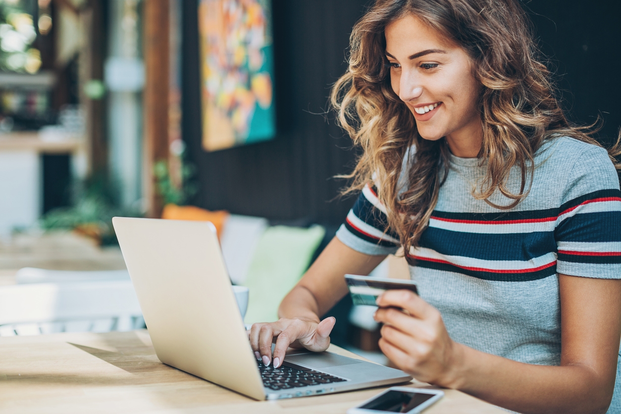 A woman uses her credit card to make an online purchase, behavior predicted through AI tools.