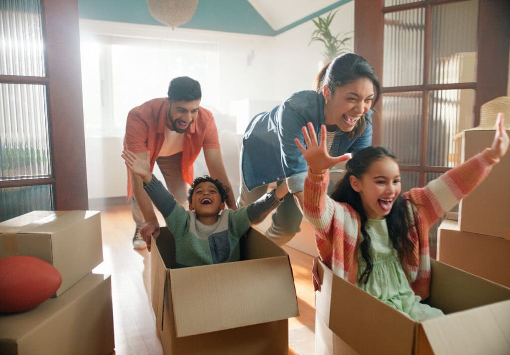 A happy family plays with kids in the living room of their new home, purchased after an effective customer engagement strategy.