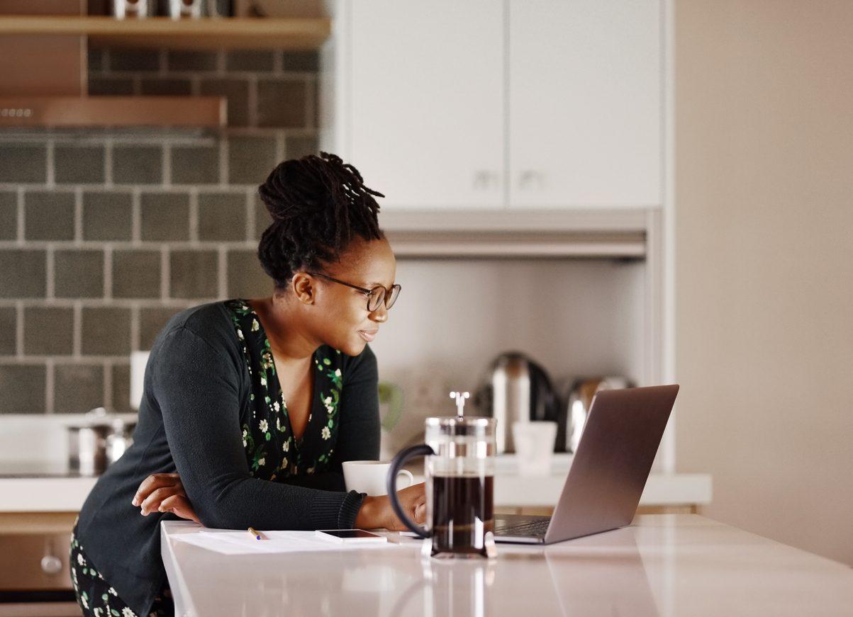 A woman researches new homes online from her laptop in her kitchen.
