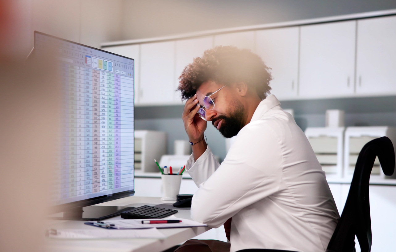 A frustrated data entry worker sits at his computer displaying his dashboard.