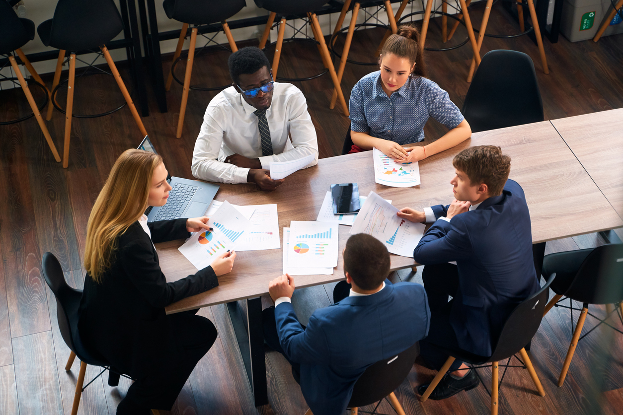 An overhead view of homebuilder staff at a table discussing options for conversational AI tools for construction.