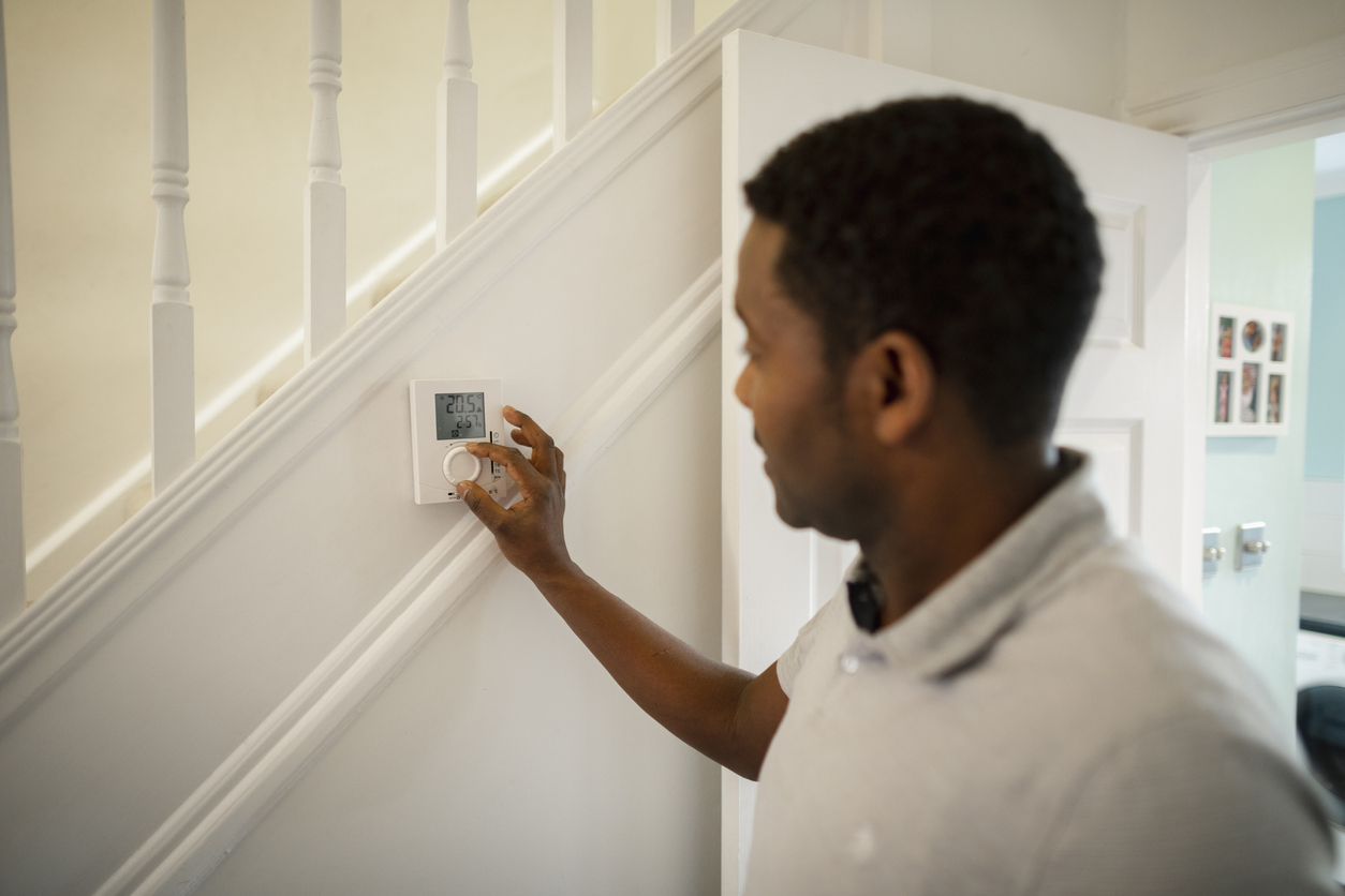 Man adjusts smart thermostat, a key homebuilding trend.