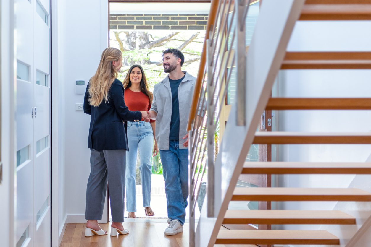 A sales rep stands at the front door, welcoming buyers to their new home. 