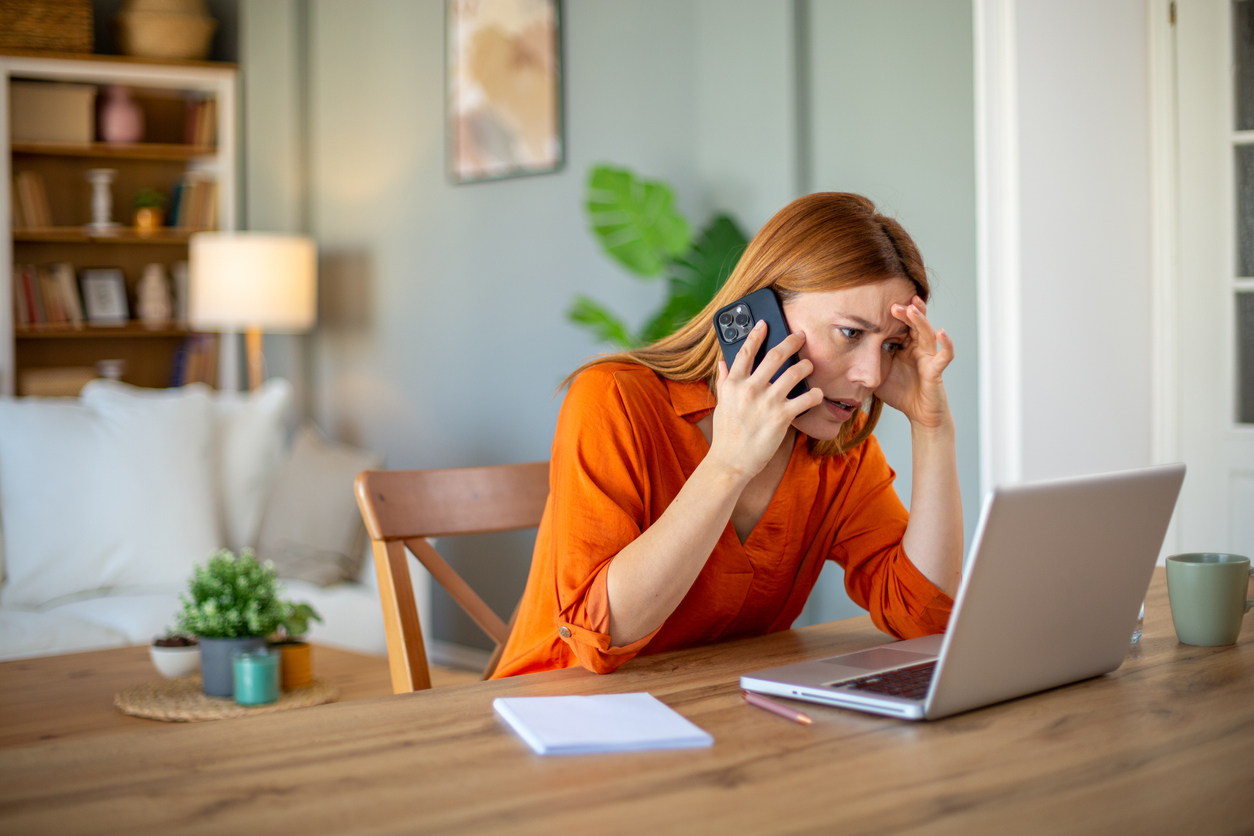 A frustrated woman is on the phone with a call center with long response times.