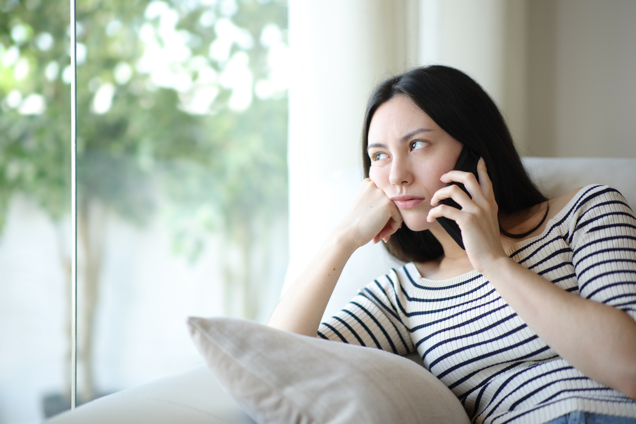 A frustrated woman is on the phone waiting for a response from a sales team that needs to learn how to follow up on leads faster.