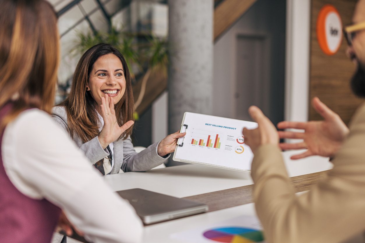 Members of the sales team sit at a table with charts to review key metrics affected by an effective homebuyer engagement strategy powered by AI tools. 