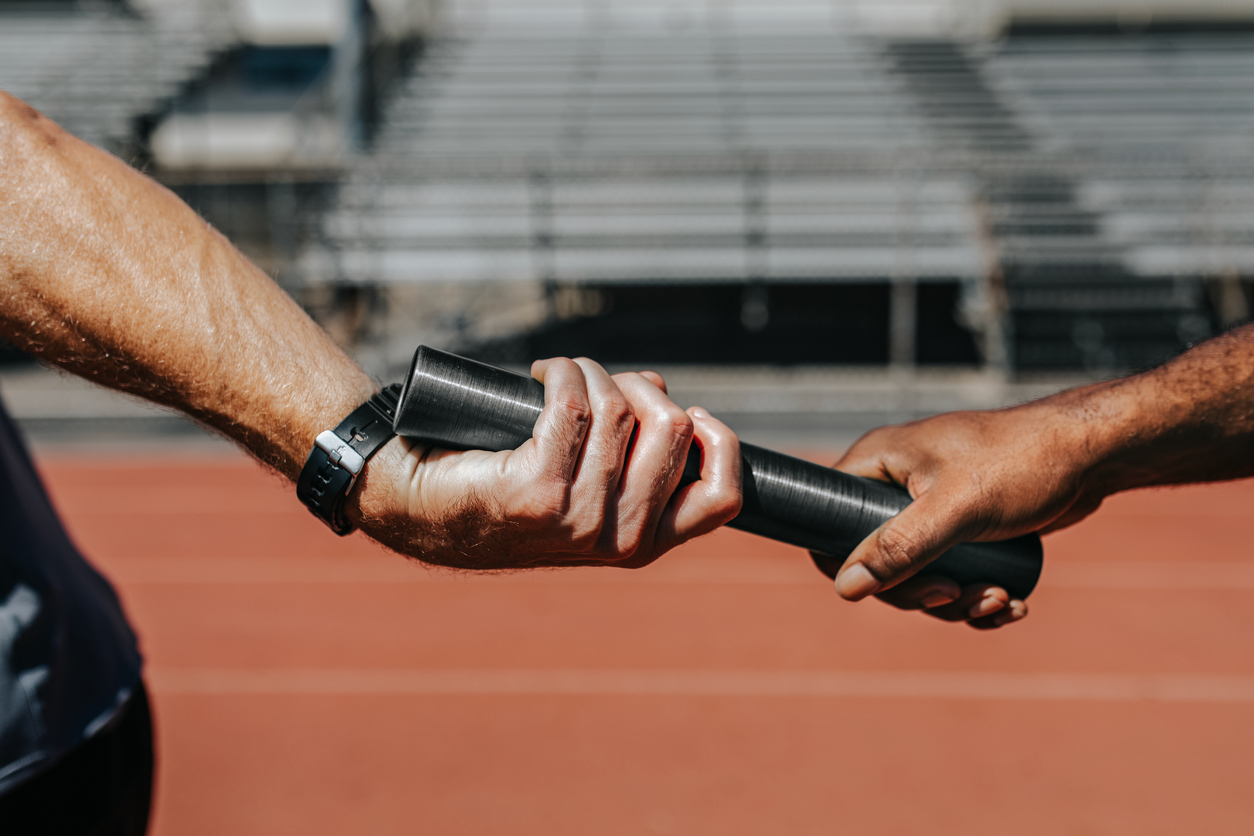 Runners in a relay race pass the baton, illustrating the important relationship between AI assistants and the humans they hand off to. 