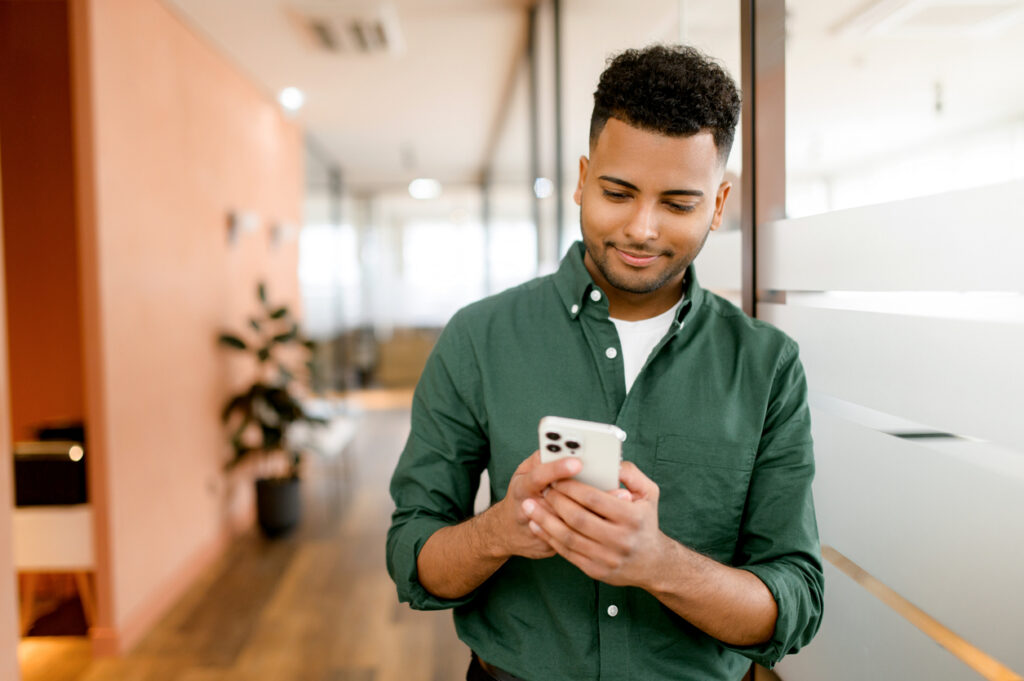 Man looks at his phone as he receives marketing both through mass text tools and SMS platforms.