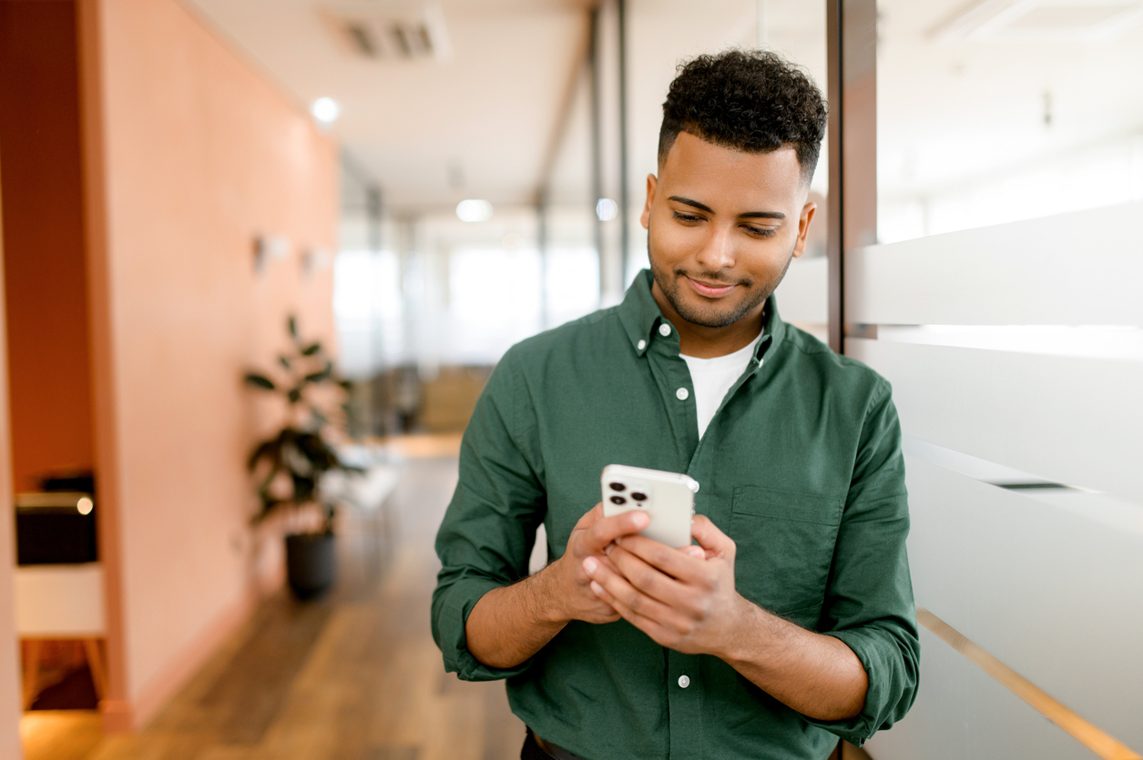 Man looks at his phone as he receives marketing both through mass text tools and SMS platforms.
