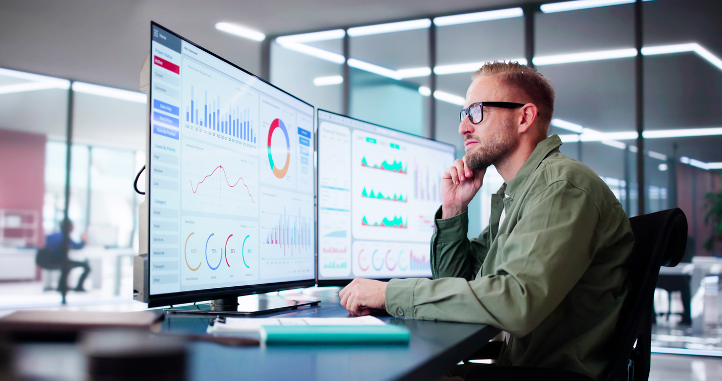 Man looks at data on his computer generated by conversational SMS tools to gain greater insight into his customers. 