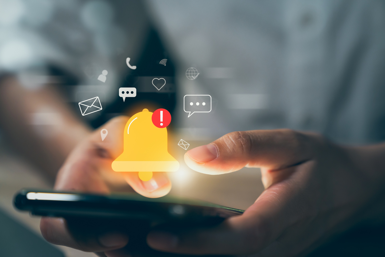 A person holds a phone with multiple reminder icons showing the capabilities of SMS lead engagement technology.