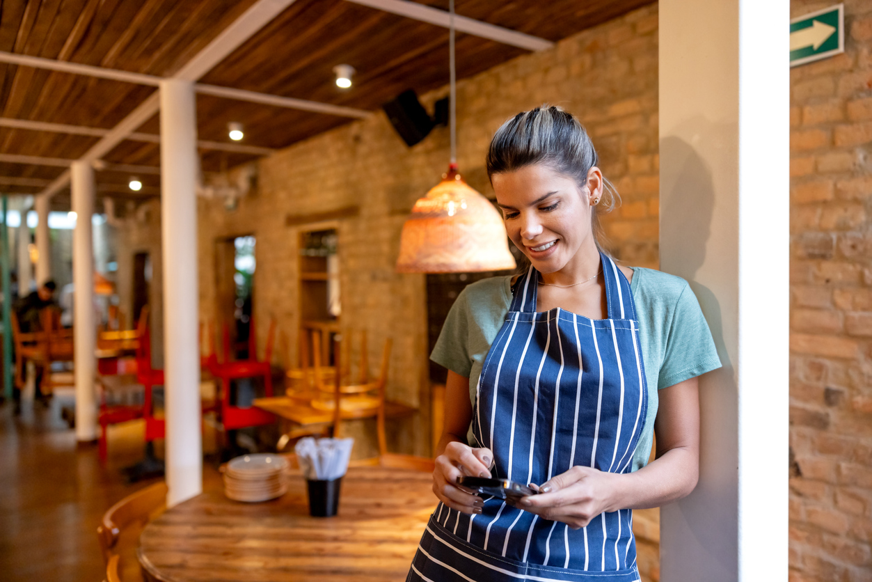 Woman uses her phone while working in a restaurant to get answers from customer service.