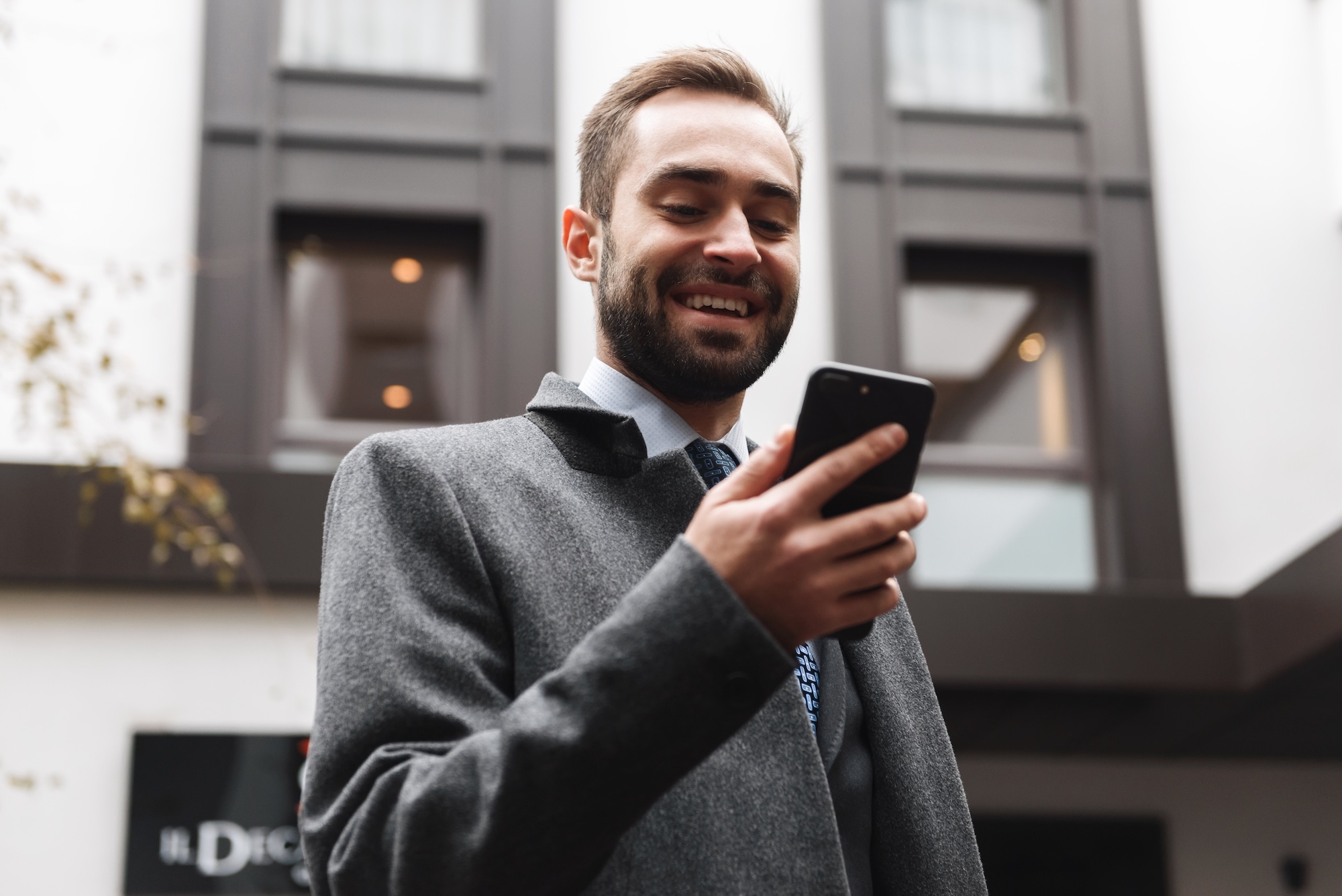 Man smiles while texting a compliant mortgage lender