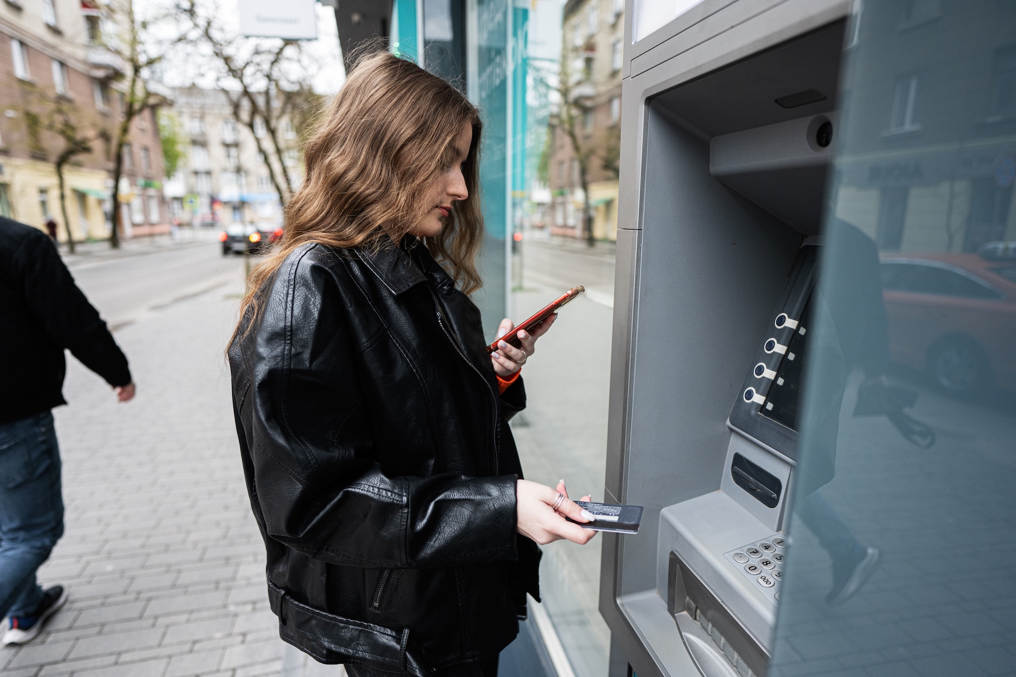 Woman uses ATM while texting with her bank